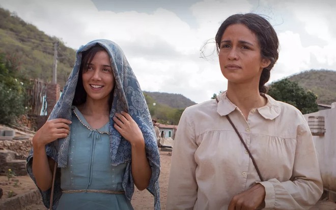 Marjorie Estiano cobre a cabeça com um lenço e Nanda Costa tem expressão séria em cena de Entre Irmãs